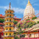 Penang Buddhist temple with golden and white pagodas, pink bougainvillea flowers, and traditional red temple structures under