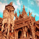 Ornate wooden temple facade with intricate carved details and pointed spires against blue sky in Pattaya, Thailand