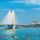Bandra-Worli Sea Link cable-stayed bridge spanning blue Arabian Sea waters with Mumbai skyline and boats in foreground