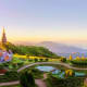 Doi Inthanon temple with golden spires at sunrise overlooking manicured gardens and mountain landscape in Chiang Mai, Thailan