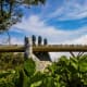 Giant stone hand sculpture emerging from ground beneath wooden bridge with tourists, Da Nang Vietnam