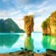 Emerald lagoon with towering limestone rock formation surrounded by lush green cliffs in Koh Samui, Thailand