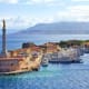 Venetian fortress with lighthouse overlooking Messina harbor and moored ships, with Calabria mountains visible across the str