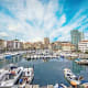 Savona harbor with moored white boats, colorful waterfront buildings, and blue sky with wispy clouds