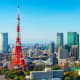 Tokyo skyline with red Tokyo Tower landmark surrounded by modern skyscrapers and clear blue sky
