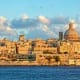 Valletta skyline with golden limestone buildings and St. Paul's Cathedral dome overlooking the Mediterranean Sea