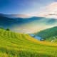 Rolling green terraced rice fields in Sa Pa valley with misty mountains and traditional farmhouse at sunrise