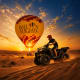 Person riding ATV in desert at sunset next to hot air balloon with "Balloon Flights" text and checkered pattern