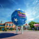 Dream World theme park entrance with large blue globe landmark, colorful buildings, and visitors in the plaza under blue sky