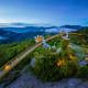 Golden Hand Bridge spanning lush mountains at dusk, Bana Hills landmark with illuminated stone hands and forested valley land