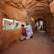 Visitors viewing a camel at Emirates Park Zoo through a carved stone window opening