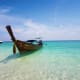 Traditional wooden long tail boat anchored in turquoise shallow water at James Bond Island, Thailand