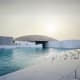Louvre Abu Dhabi museum with distinctive dome reflected in waterfront lagoon at sunset