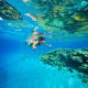 Snorkeler swimming underwater above coral reef in clear blue ocean near Nusa Penida