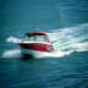 Red and white speedboat navigating through blue ocean waves near Phi Phi Island