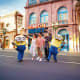 Family posing with two Minion characters in front of Minion Market attraction at Universal Studios Singapore