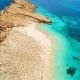 Aerial view of Damaniyat Island's white sand beach with turquoise waters and rocky coastline