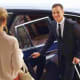 Professional chauffeur opening car door for passenger during intercity transfer service
