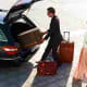 Man and woman loading luggage into car trunk at airport dropoff zone