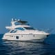 Luxury white motor yacht anchored in clear blue ocean water under cloudless sky