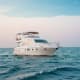 Luxury white motor yacht anchored in calm blue ocean waters during daytime