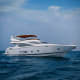 Luxury white motor yacht with extended canopy anchored in calm blue ocean waters under clear sky