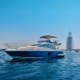 Luxury blue and white motor yacht anchored in turquoise water with Burj Al Arab sail-shaped hotel visible in background, Duba