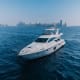 Luxury white motor yacht anchored in blue water with Dubai skyline in background