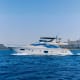 Luxury white and blue yacht with multiple decks moored in clear turquoise water near coastal buildings