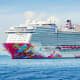Genting Dream cruise ship with colorful pink and blue hull design sailing in blue ocean waters