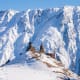 Snow-covered mountain peaks with ancient stone church nestled on hillside in winter landscape, Georgia