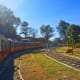 Red and orange vintage train on curved railway tracks in green landscape with trees under clear blue sky
