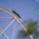 Roller coaster ride with passengers on track against blue sky at amusement park