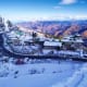 Snow-covered mountain resort town with hotels and buildings nestled in valley surrounded by snow-capped Himalayan peaks under