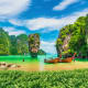 Turquoise waters and limestone cliffs of Phang Nga Bay with traditional longtail boats anchored near James Bond Island in Phu