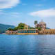 Jag Mandir palace reflected in Lake Pichola waters with green hills and blue sky in Udaipur, Rajasthan
