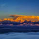 Snow-capped Himalayan mountain peaks glowing golden at sunrise above a sea of clouds in Sikkim region