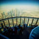 Tourists viewing Dubai skyline from observation deck with downtown buildings and desert landscape visible below