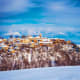 Sighnaghi historic town perched on snowy hillside with church spire visible against blue sky and white clouds, winter landsca