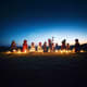 Group of people sitting in circle with lit candles on desert sand at dusk with blue twilight sky