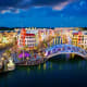 Colorful waterfront buildings and illuminated bridge over canal at dusk in Vietnamese resort town