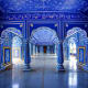 Ornate blue and white corridor with decorated arches, pillars, and intricate floral patterns in traditional Indian palace arc