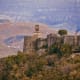 Ancient stone fortress with clock tower overlooking Albanian mountain valley and forested hillside