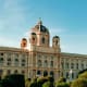 Natural History Museum Vienna with ornate dome and manicured gardens under blue sky