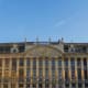Historic ornate building with gold decorative elements and mansard roof in Brussels, Belgium, under clear blue sky