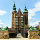 Rosenborg Castle in Copenhagen, Denmark, with green copper spires and oxidized lion statues guarding the entrance gate