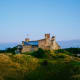 Lohesalu Castle ruins perched on a grassy hilltop in Estonia, with blue sea and sky in background