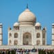 Taj Mahal front facade with domes and minarets against clear blue sky with tourists gathered in courtyard