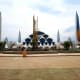 Modern white architectural complex with ornate spires and solar panels in Indonesia, surrounded by palm trees and paved plaza