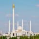Hazrat Sultan Mosque in Astana, Kazakhstan with white marble architecture and golden spire against blue sky